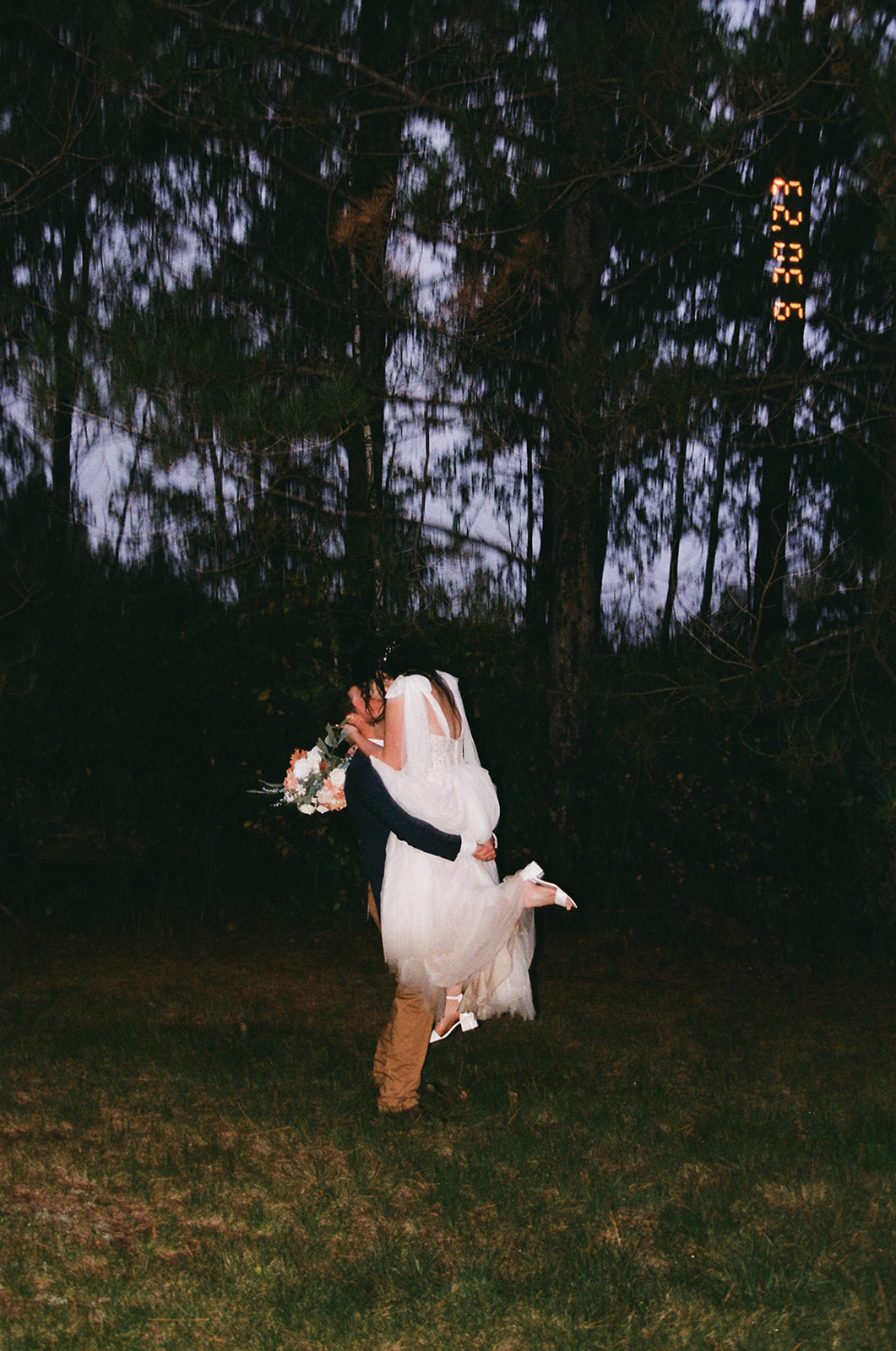 groom lifts the bride into the air during blue hour portrait session