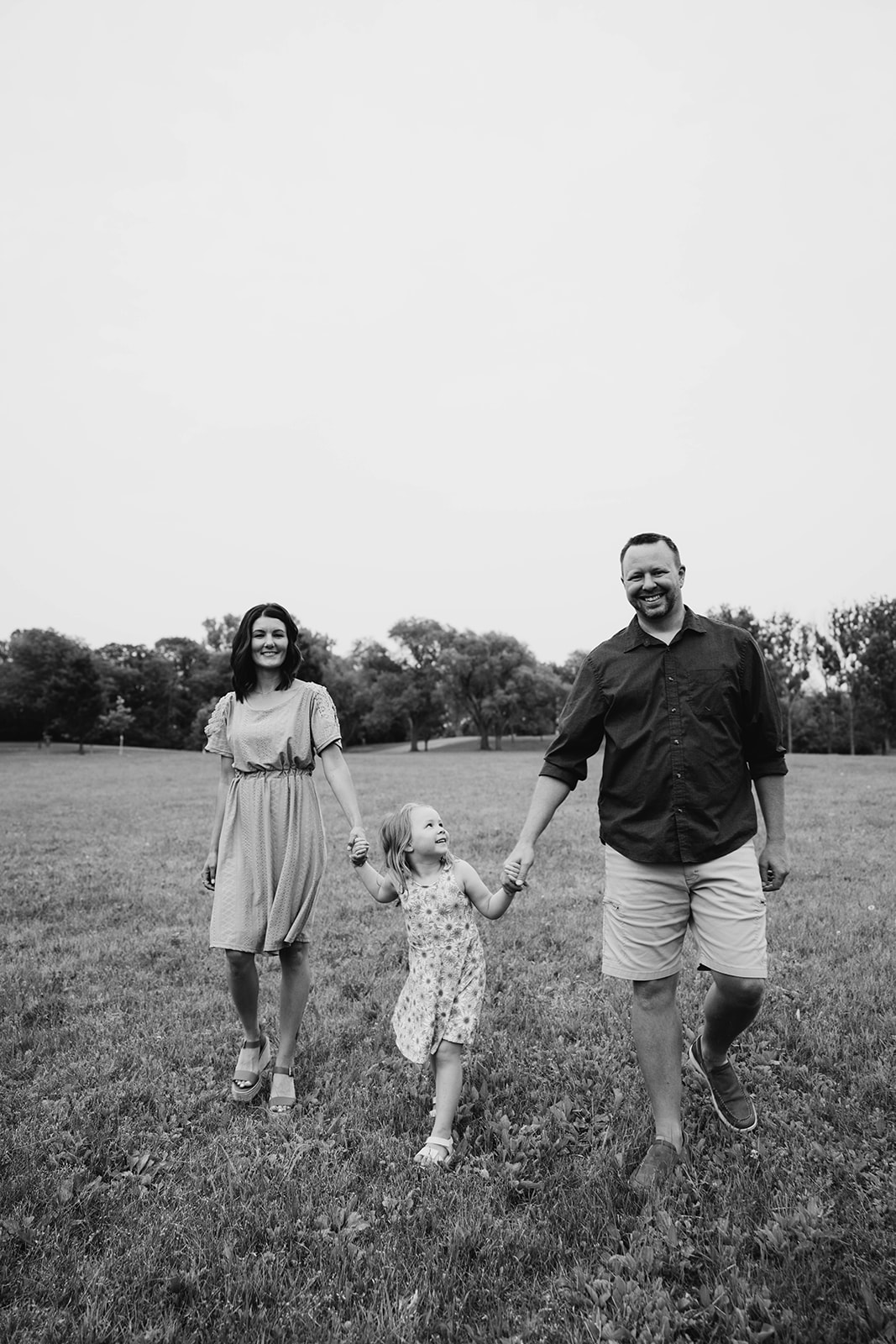 Minnesota family photographer takes picture of parents holding thier kid's hands in Rochester MN
