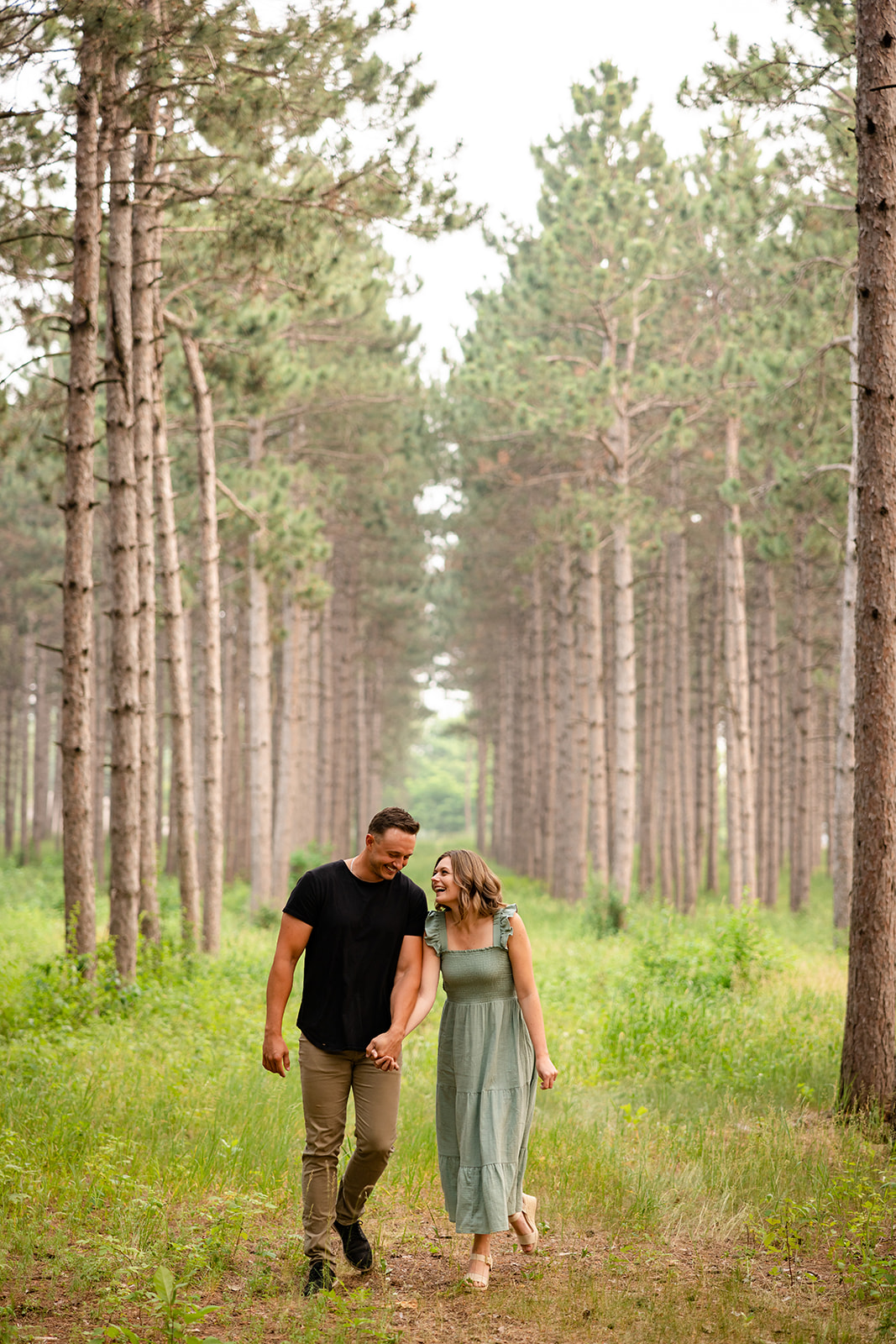 Couple walking in pine trees engagement session picture